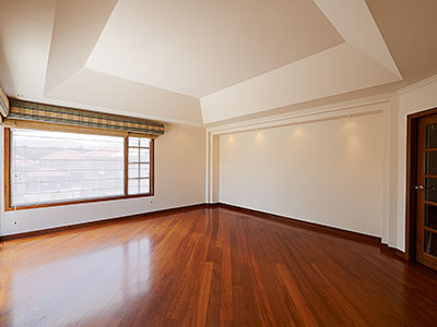 Living room floor that has been restored. Large rectangular window with sunlight shining in.