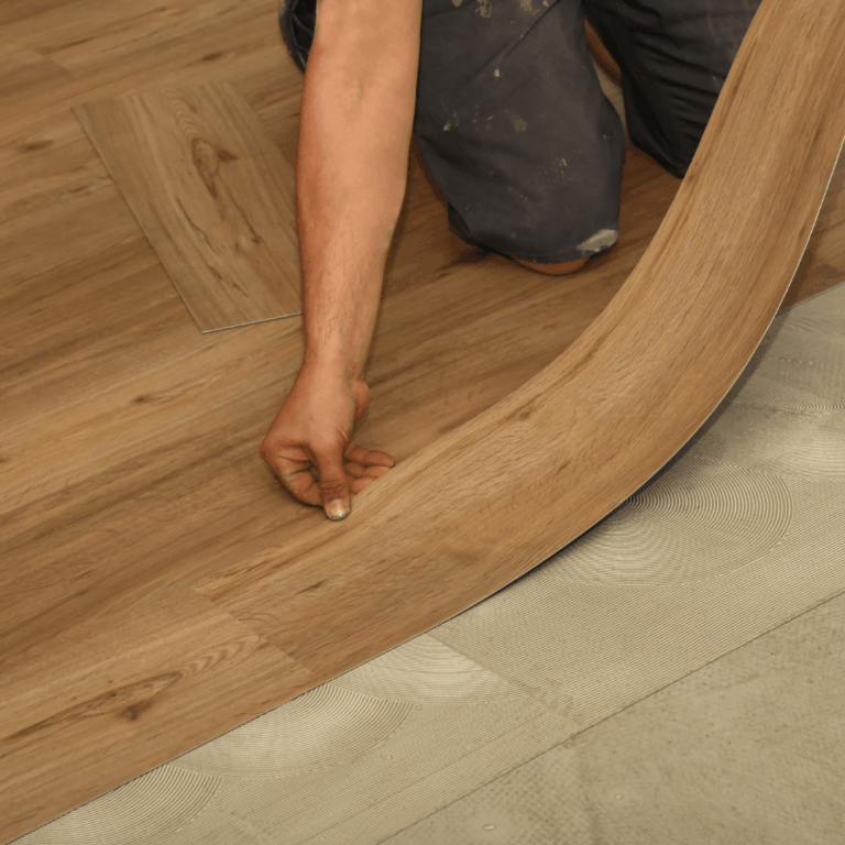 A person smoothly installing laminate flooring planks with a curved edge.