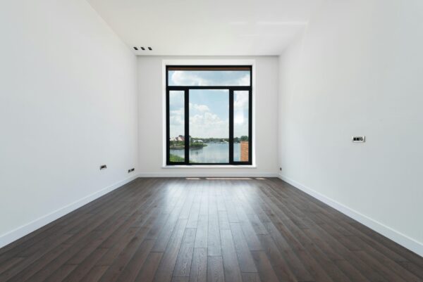 Bright, spacious room featuring large window with a view of a lake.